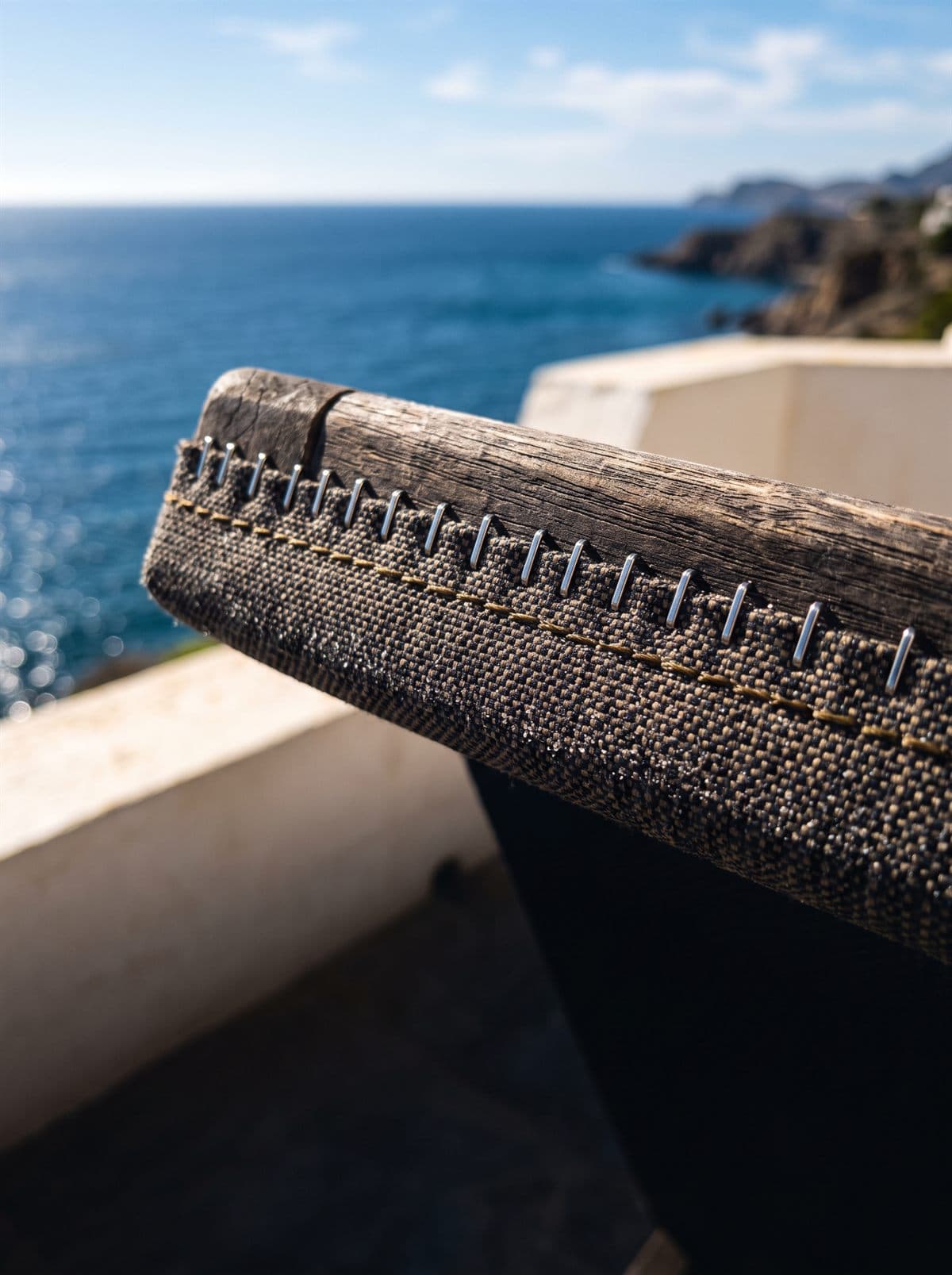 Detalle de grapado sobre tejido técnico en el canto de un cojín de exterior junto al mar